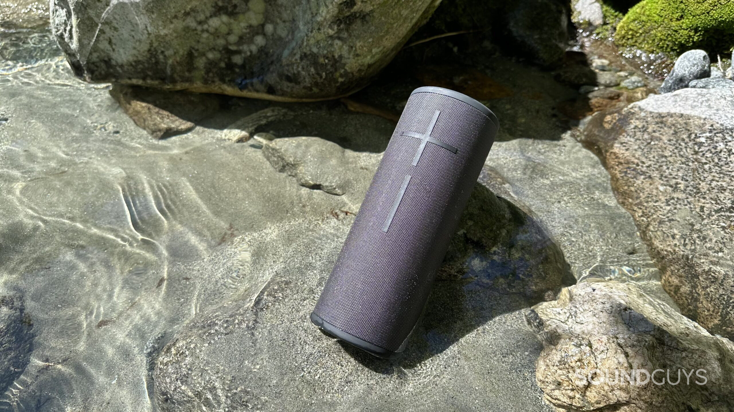 The UE MEGABOOM 3 on some sand on shallow water.