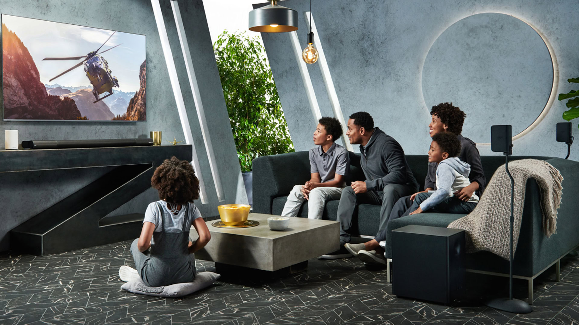 This is a photo of a family sitting in the living room watching TV and using the Vizio Elevate Soundbar System to listen to their movie.