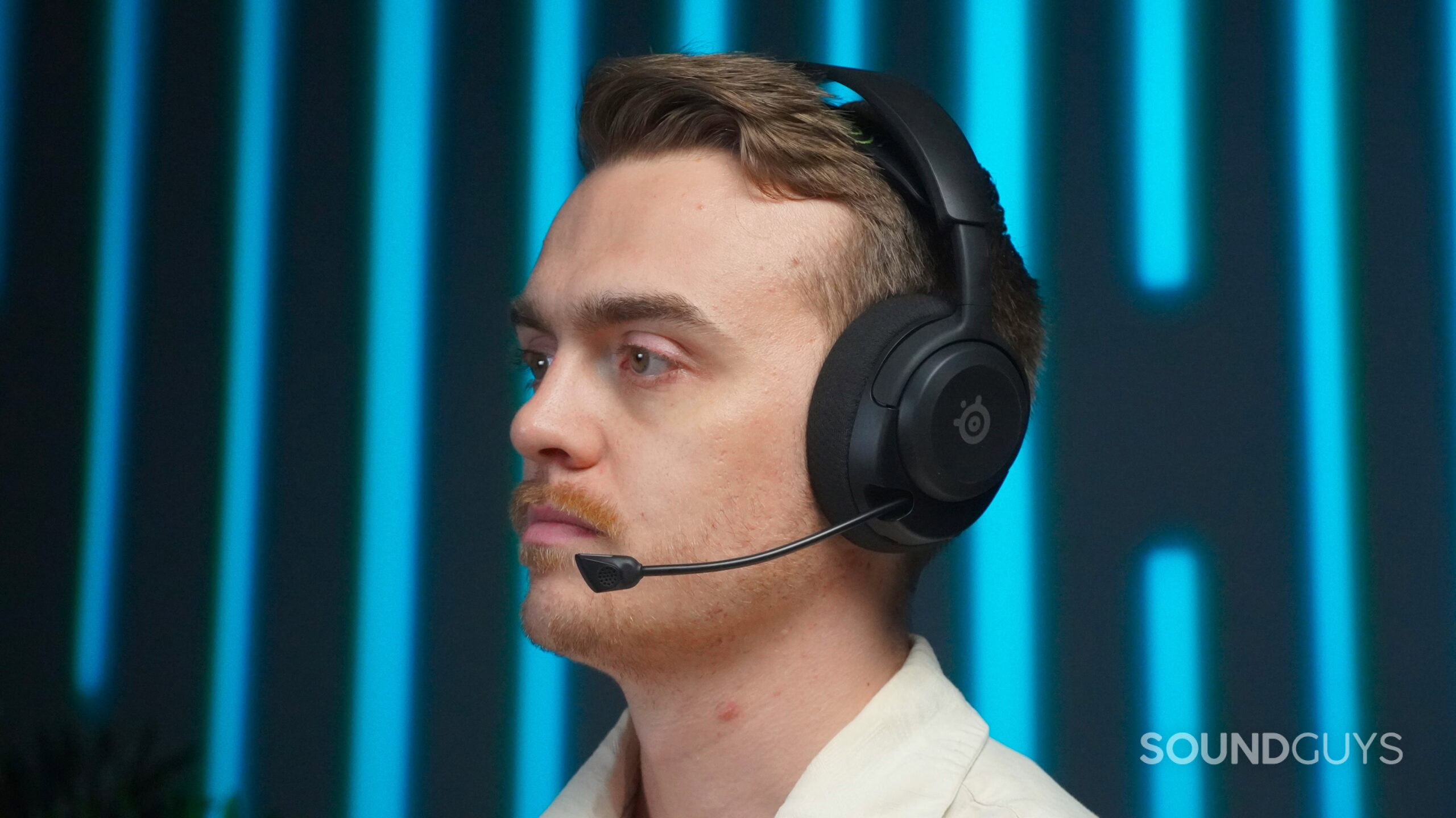 A handsome, well-dressed man wearing the steelseries arctis nova 5x gaming headset