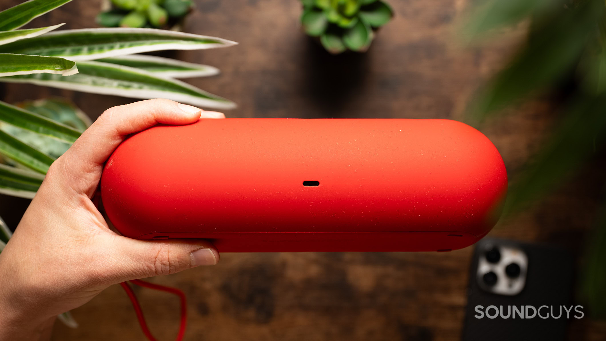 A hand holds the Beats Pill showing its USB-C charging port. 