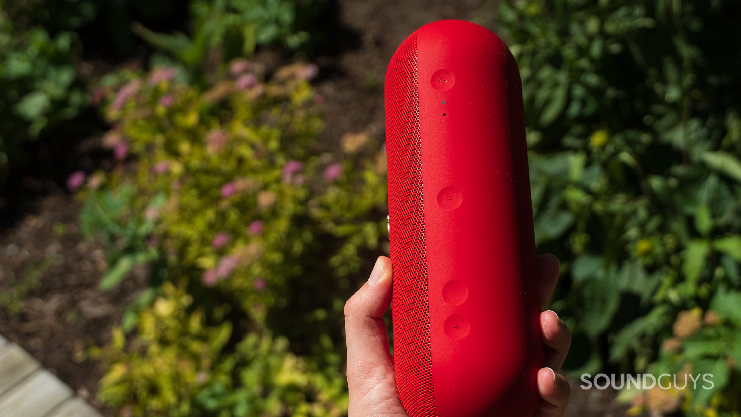 A hand holds the Beats Pill showing the onboard controls.