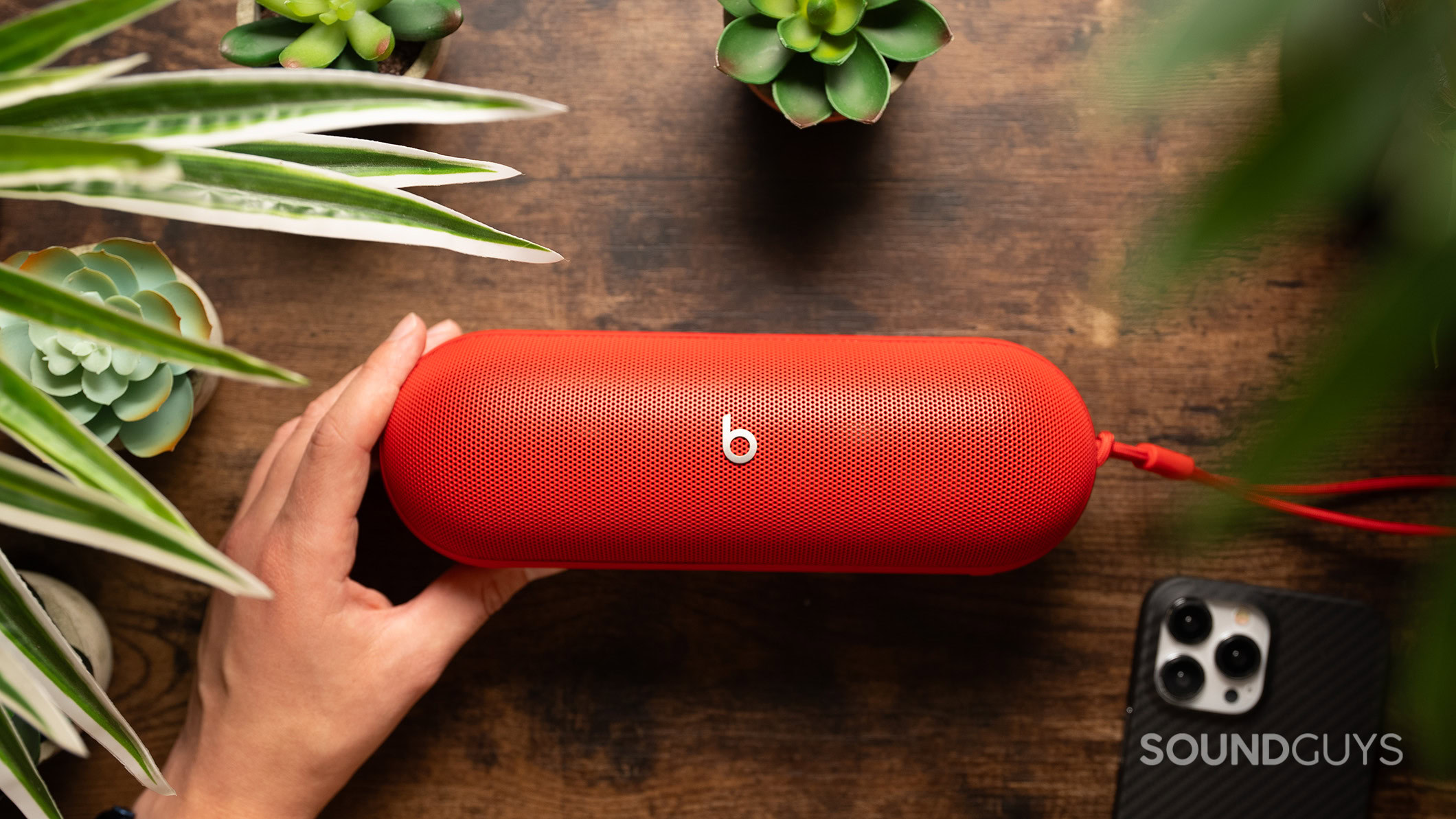 Beats Pill on a table next to plants and a phone.