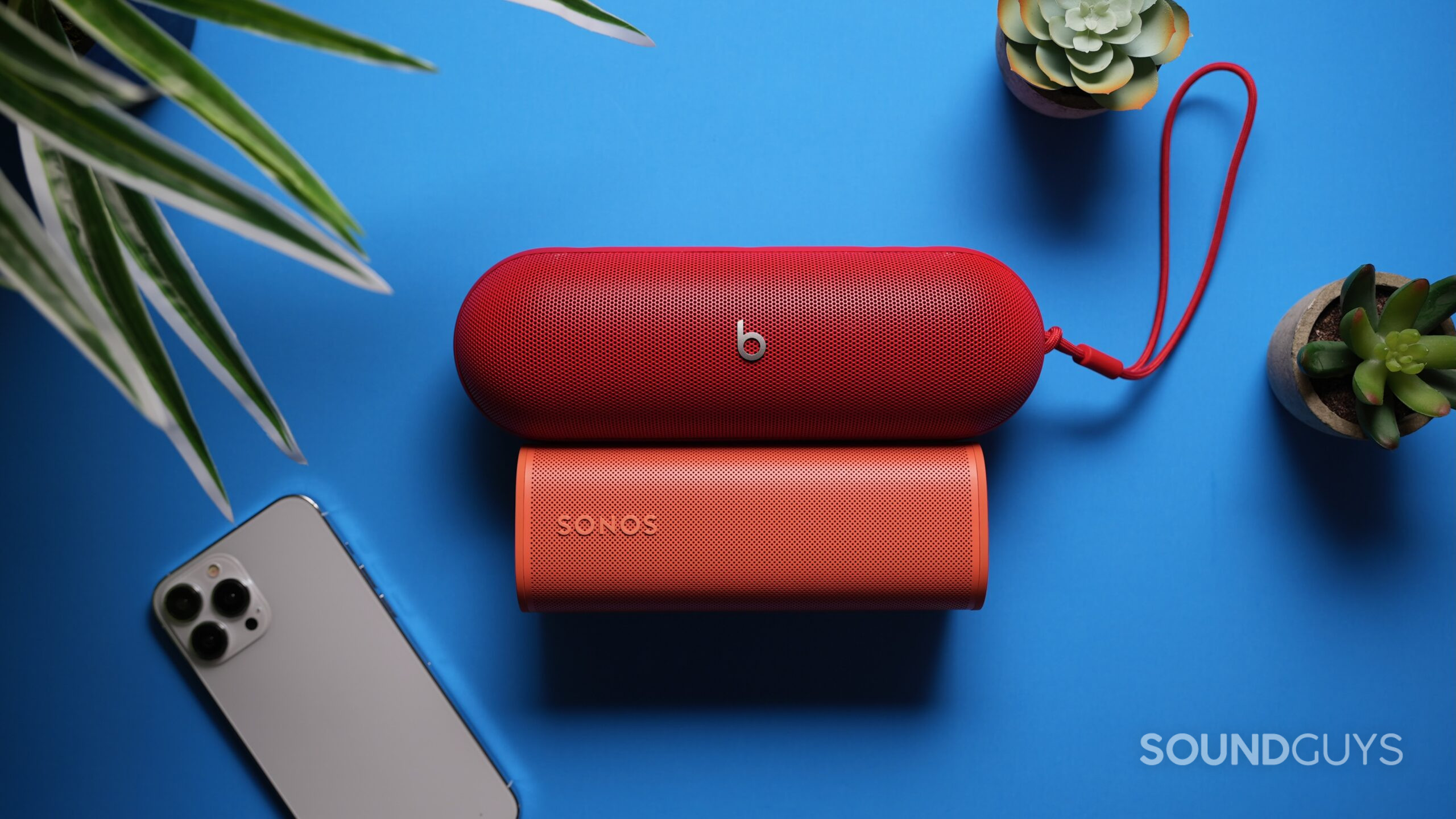 Top down shot of a Beats Pill above a Sonos Roam 2 with am iPhone 15 nearby