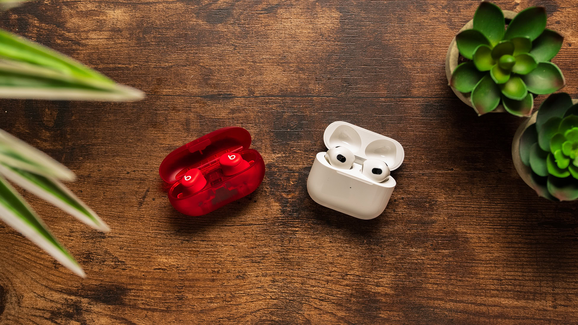 The Beats Solo Buds and AirPods (3rd generation) rest on a wooden surface.