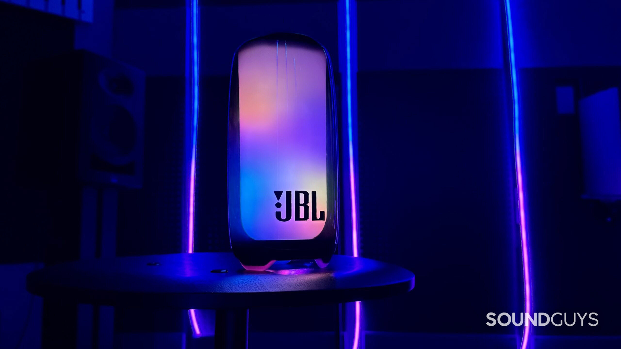 A lit up JBL Pulse 5 in a cool looking room with LED lights.