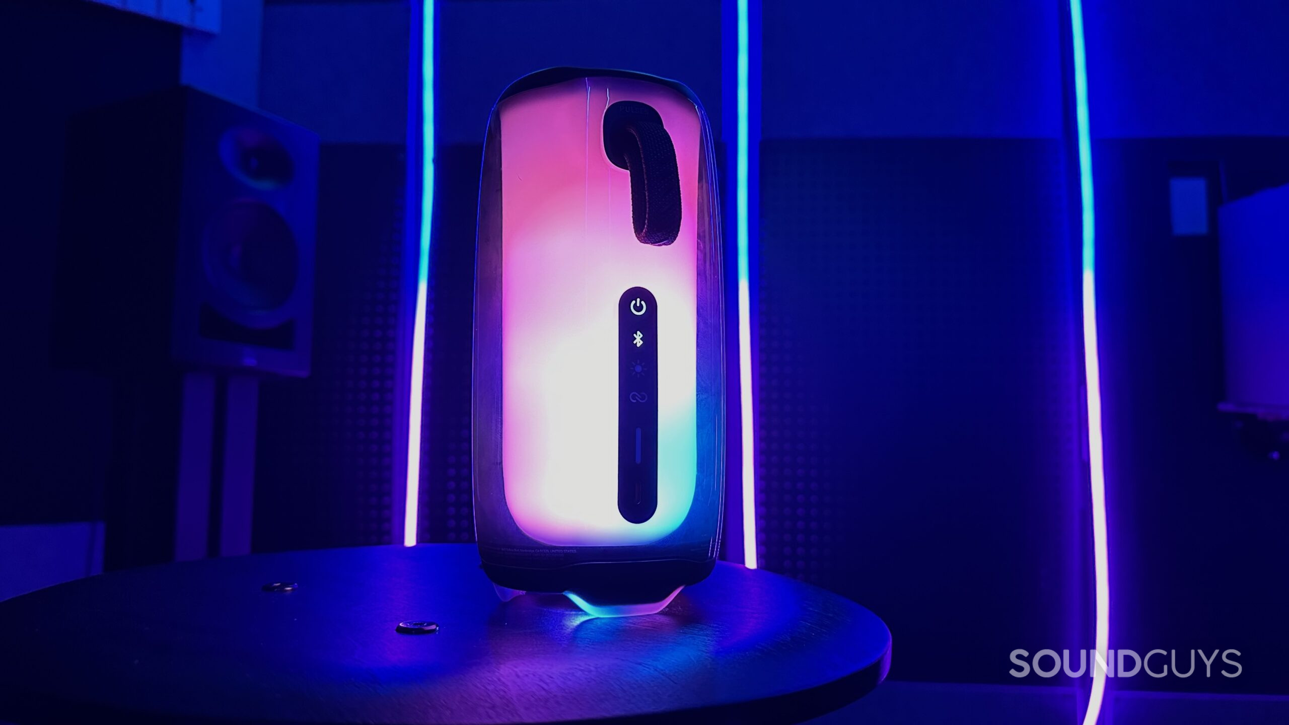 A JBL Pulse 5 lit up in a cool looking room, showing it's rear control panel and loop attachment.