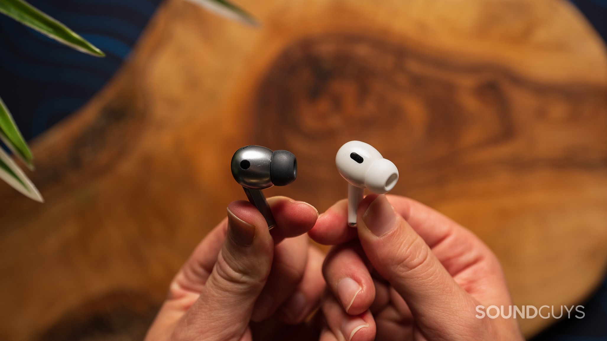 A hand holds a Samsung Galaxy Buds3 Pro earbud and a Apple AirPods Pro (2nd generation) earbud.