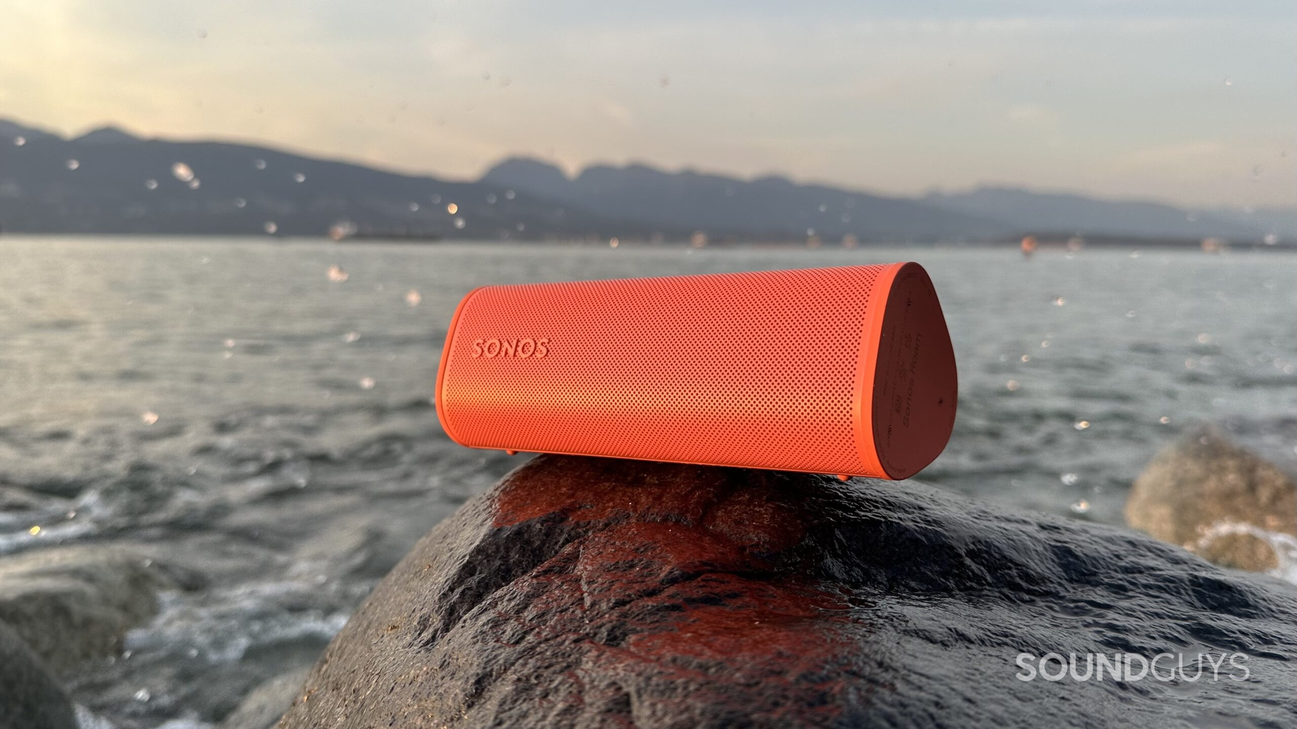 Sonos Roam 2 speaker placed on a rock beside the ocean.