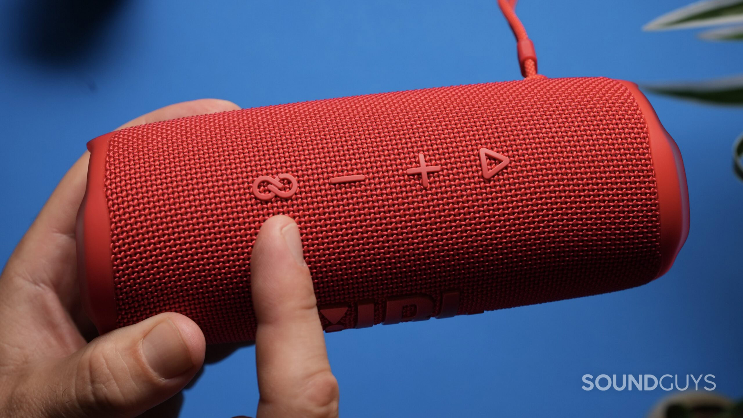 A finger points to the Party Connect button on a red JBL Flip 6