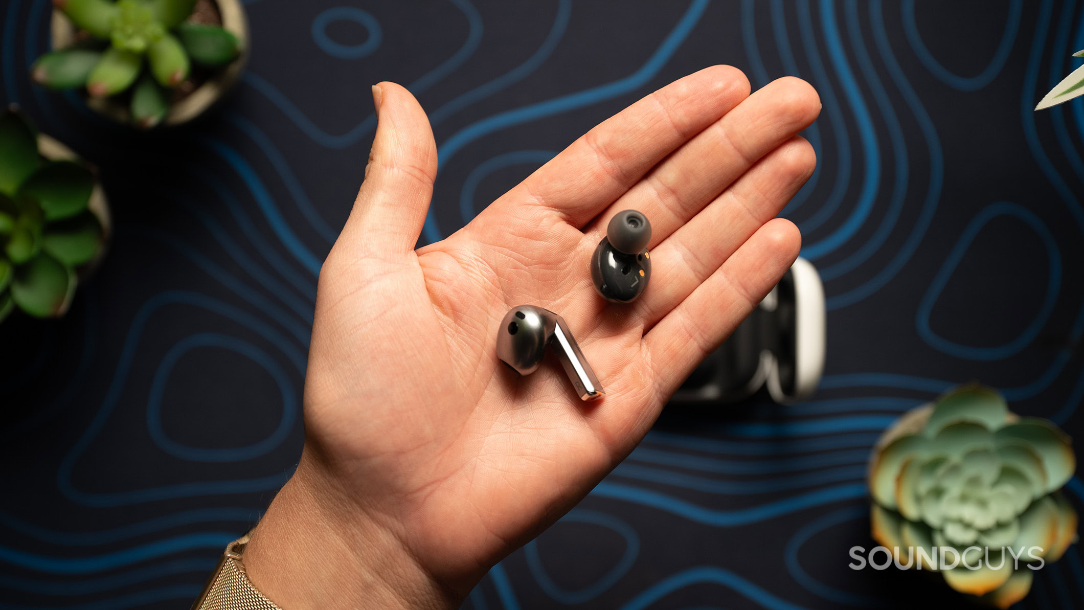 A hand holding a Galaxy Buds2 earbud and a Galaxy Buds3 earbud.