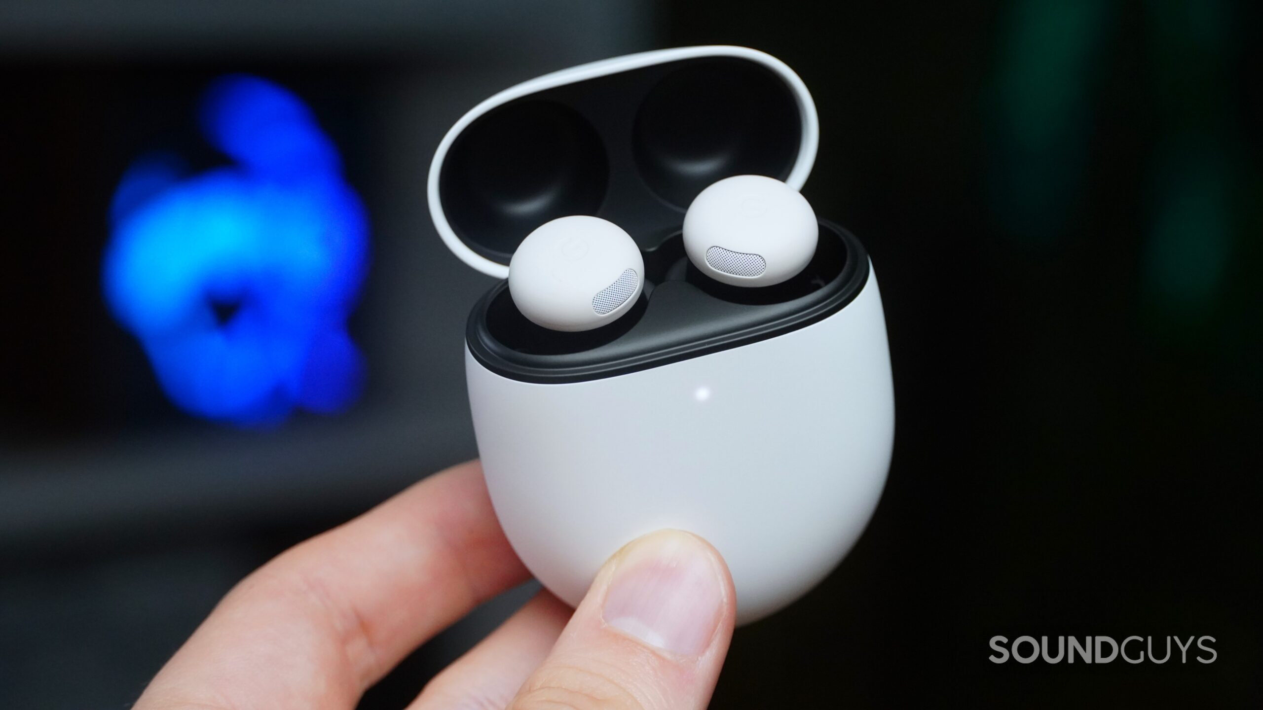 A hand holds the Pixel Buds Pro 2 in white.