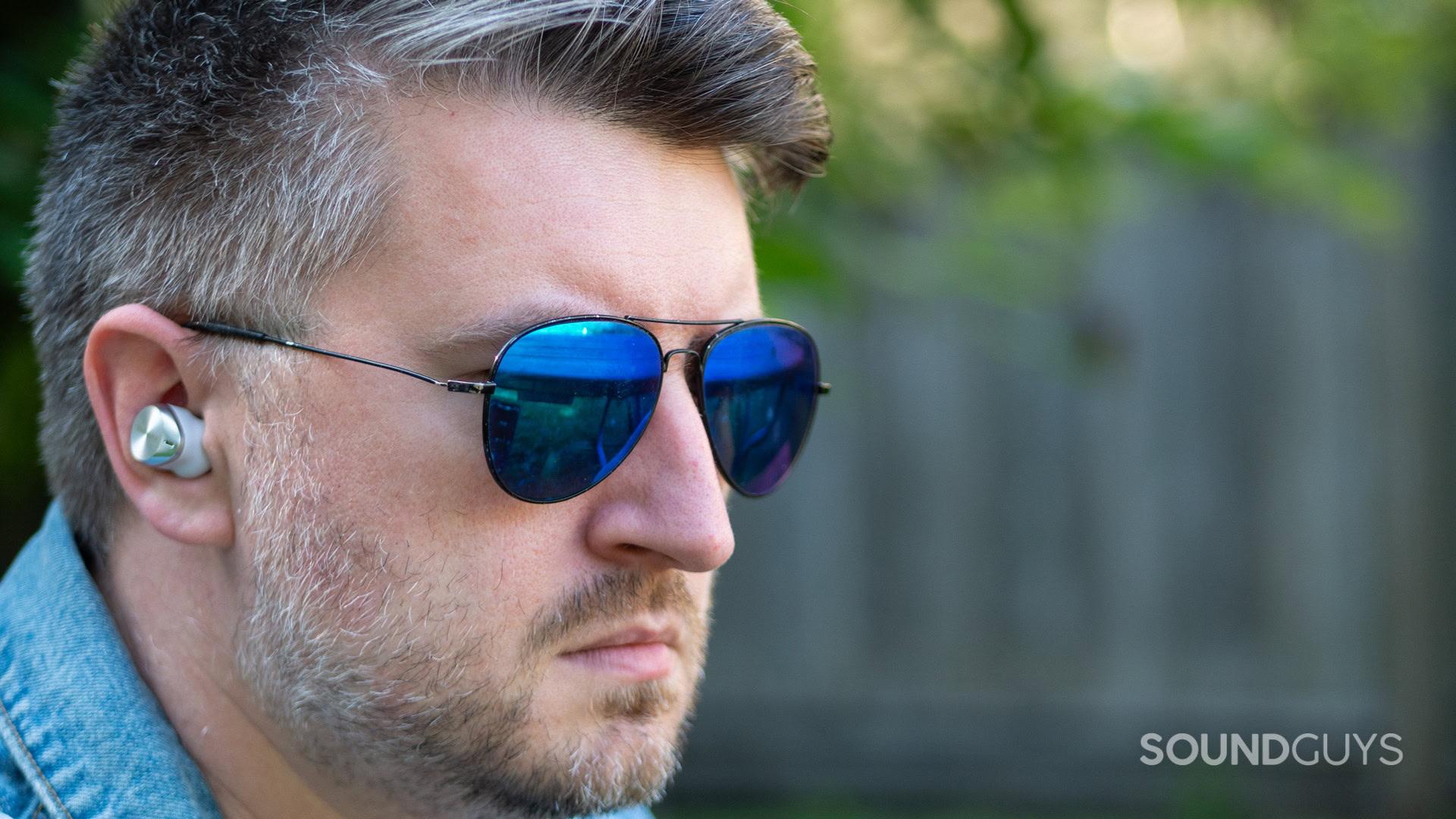 A man wearing a denim jacket listens to the Technics EAH-AZ80.