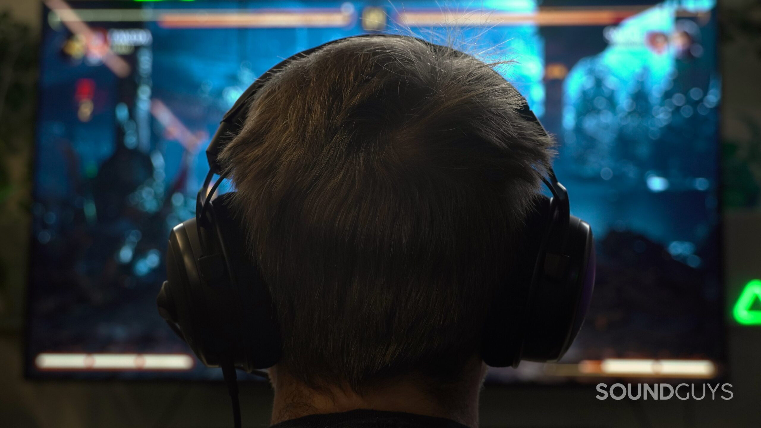 the back of a mans head wearing headphones in front of a television