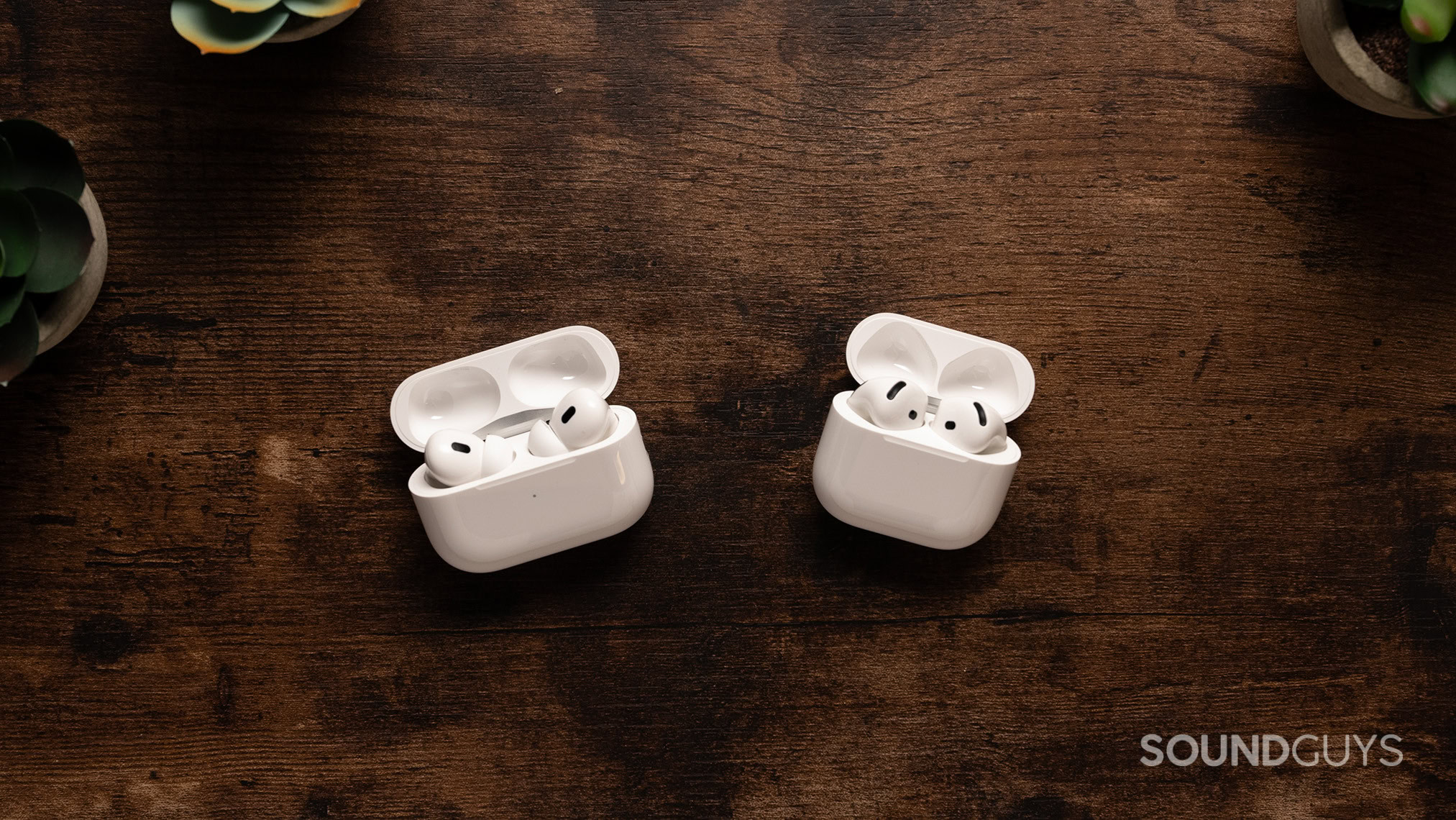 AirPods Pro 2 in their case next to the AirPods 4 with Active Noise Cancellation in their case. 