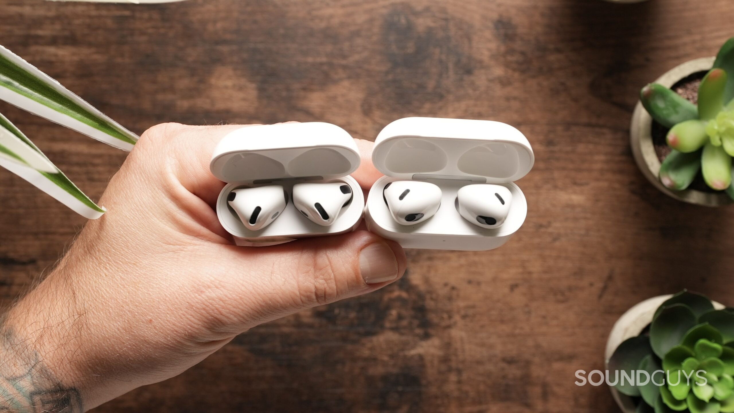 Top down view of an open AirPods 4 case, next to and open AirPods 3 case.