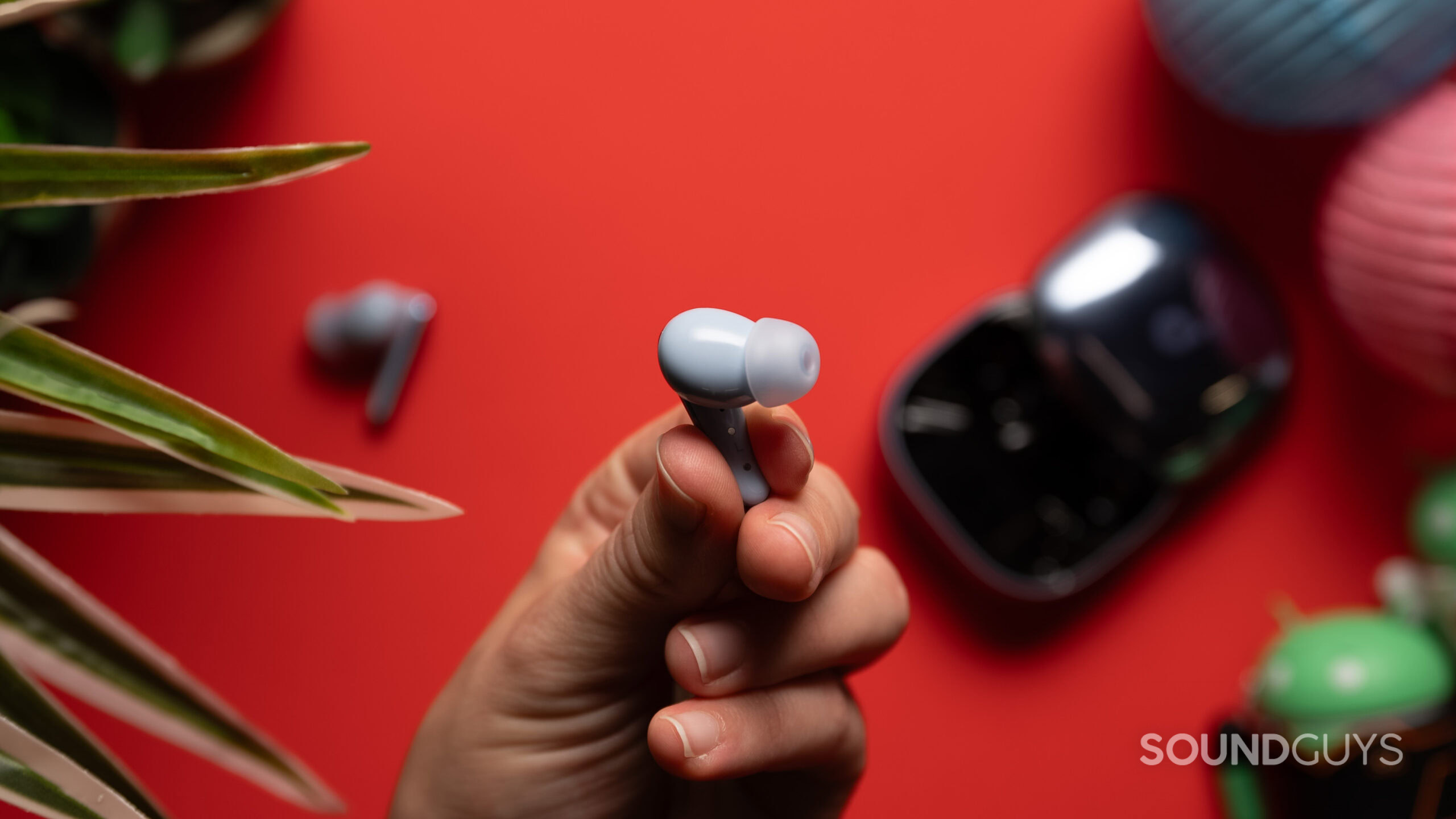 A hand holds an Anker Soundcore Liberty 4 Pro earbud. 