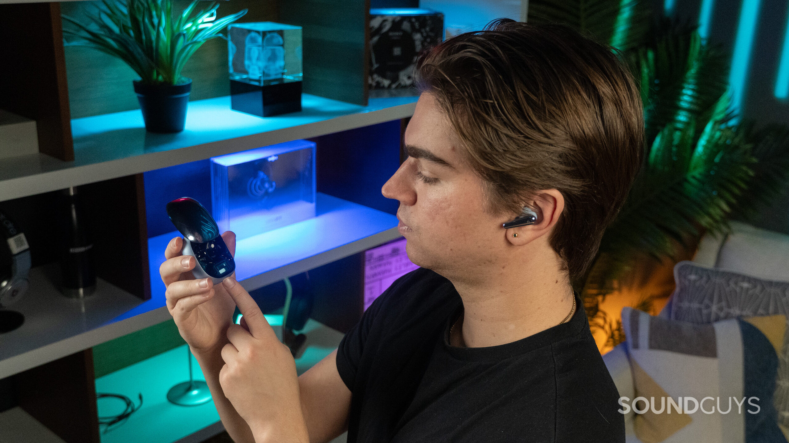 A man wearing the Anker Soundcore Liberty 4 Pro, using the touchbar on the charging case.