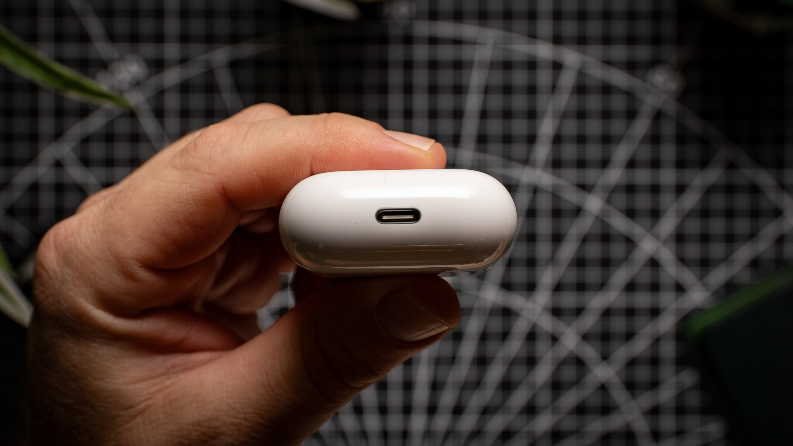 A hand holds the AirPods 4 charging case, showing the USB-C port. 