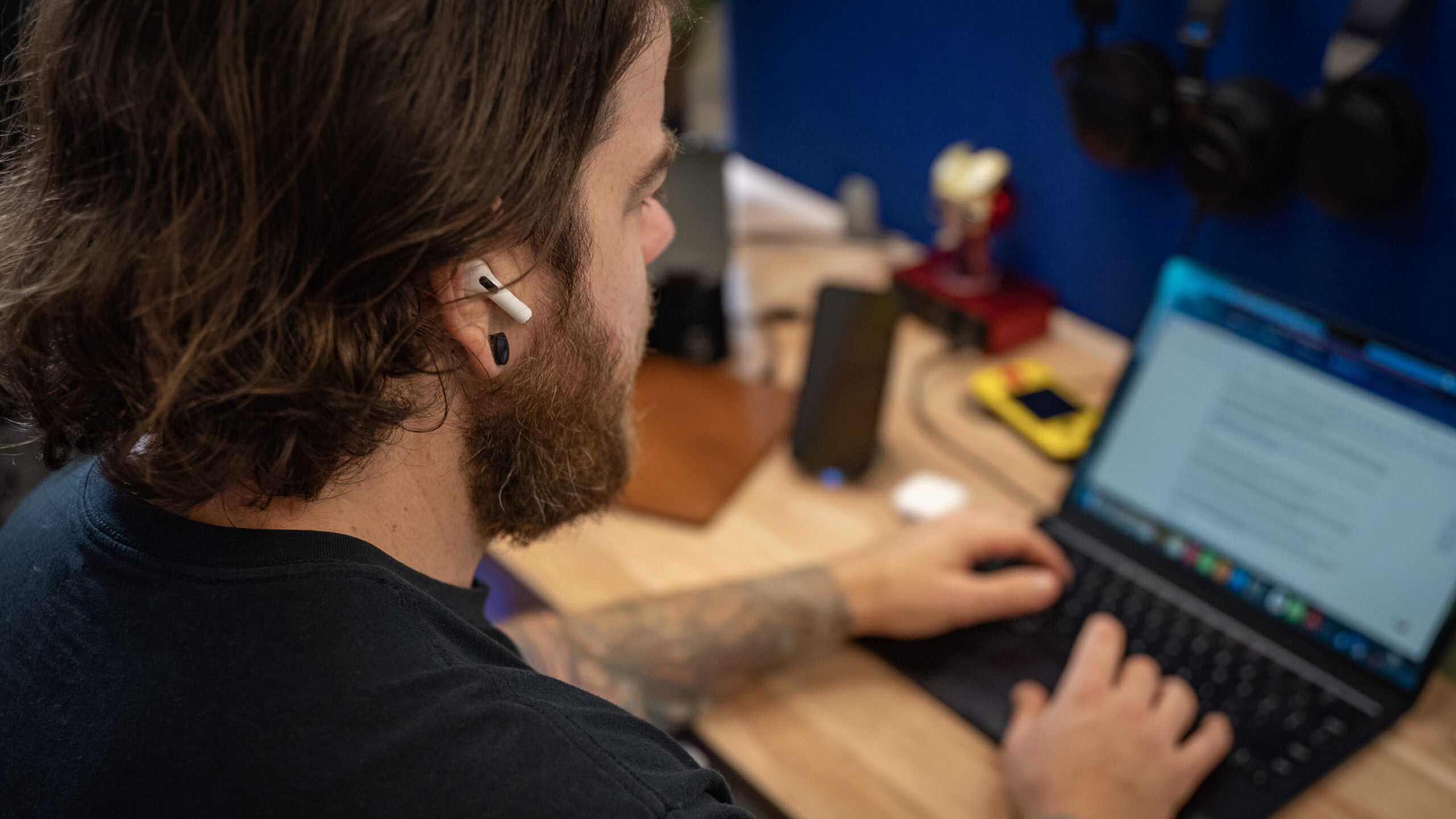 A man working on a laptop wearing the airpods 4