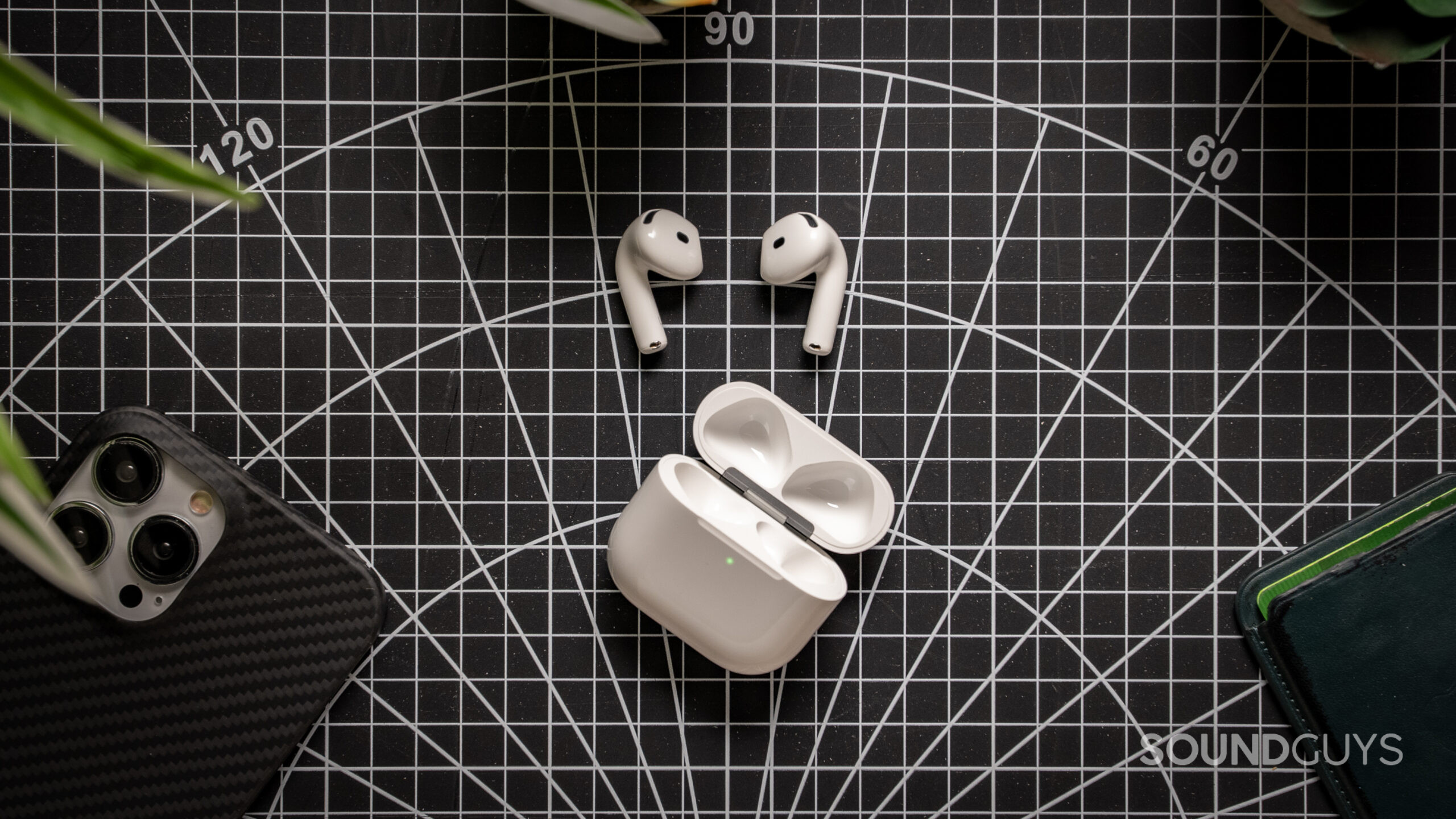 AirPods 4 earbuds next to their case on a table. 