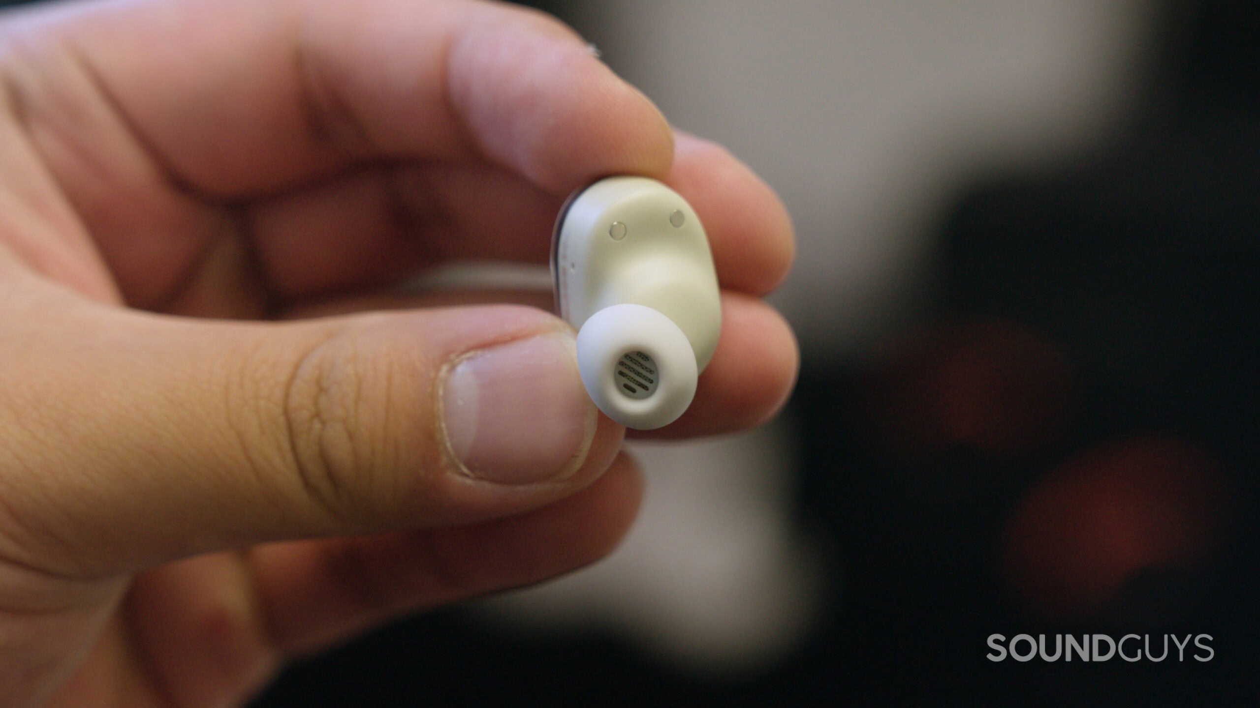 A hand holding the Beyerdynamic AMIRON 300 earbuds. 