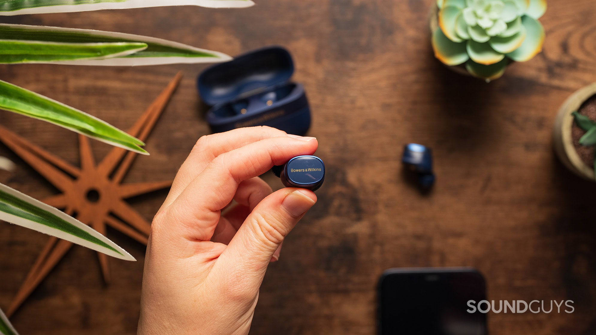 A hand holding the Bowers & Wilkins Pi8 earbud.