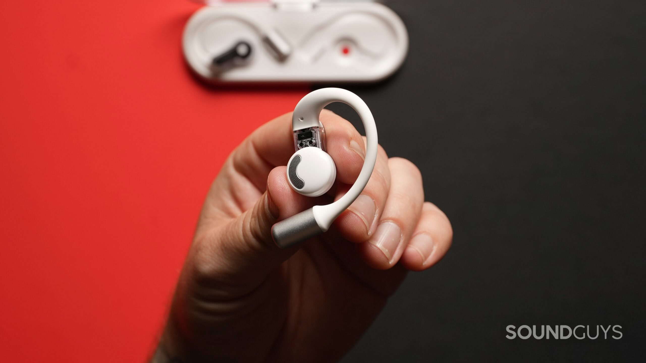 Top down photo of a hand holding a Nothing Ear (Open) earbud, showing its innerside.-