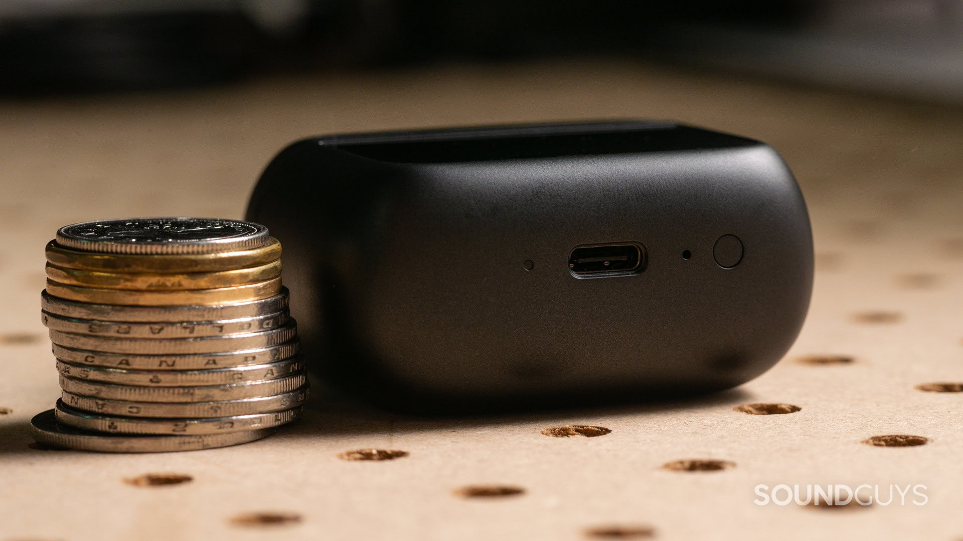 A photo of the JBL Tour Pro 3's Smart Charging Case, next to a stack of coins.