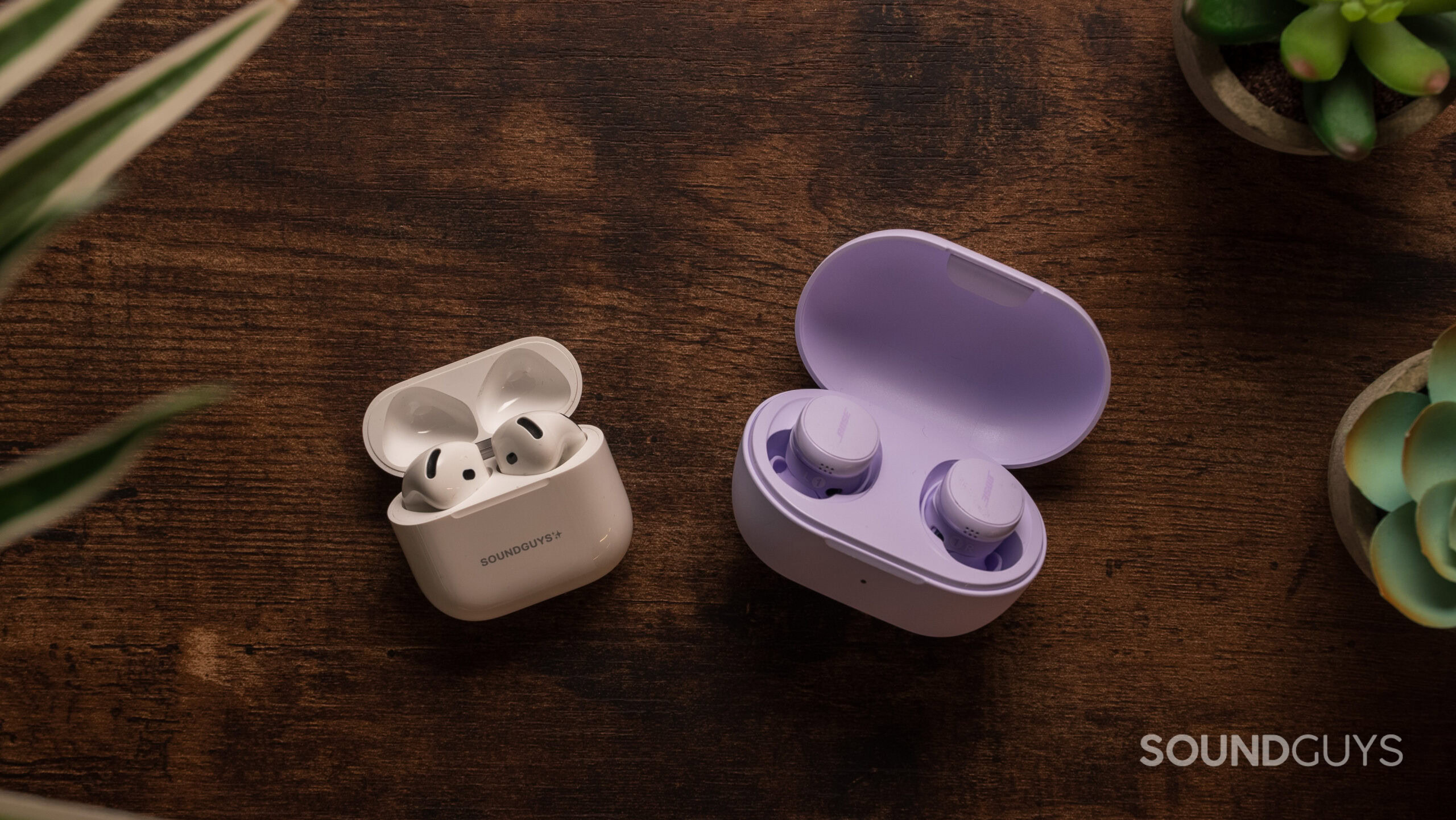 AirPods 4 with Active Noise Cancellation next to Bose QuietComfort Earbuds (2024) with the earbuds inside the charging case.