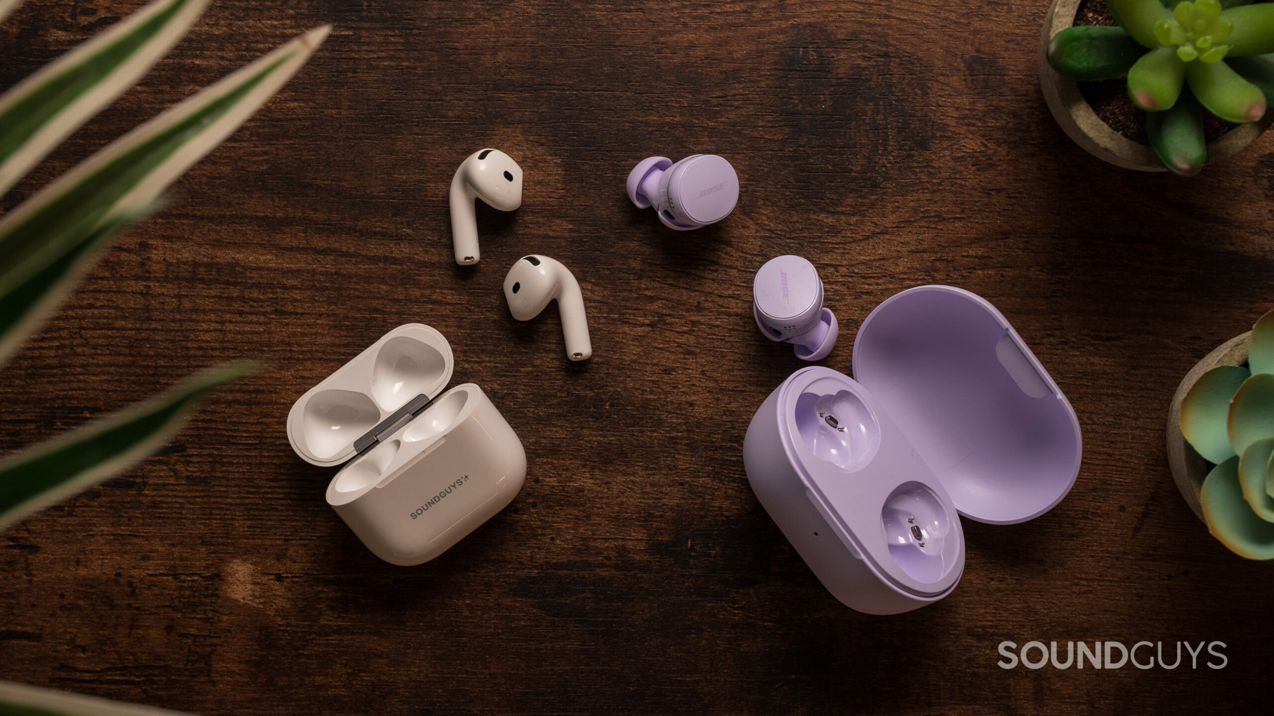 AirPods 4 with ANC earbuds next to Bose QuietComfort Earbuds outside of their case. 