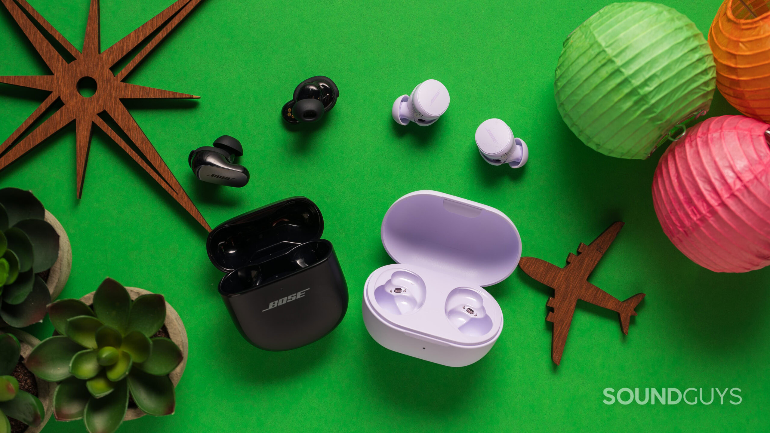 Bose QuietComfort Earbuds next to Bose QuietComfort Ultra Earbuds on a table with the earbuds next to the case. 