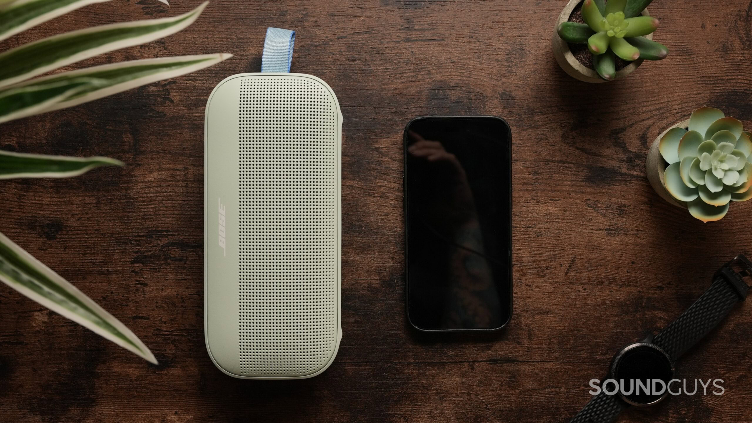 Top down photo of a Bose SoundLink Flex Gen 2 speaker, next to an iPhone 14 Pro.