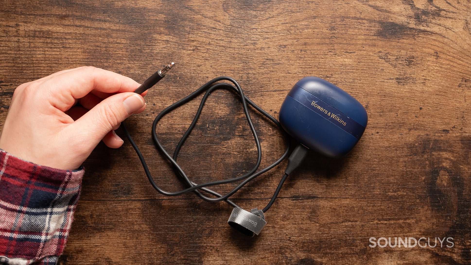 A hand holding the 3.5mm transmitter cable for the Bowers &amp; Wilkins Pi8.