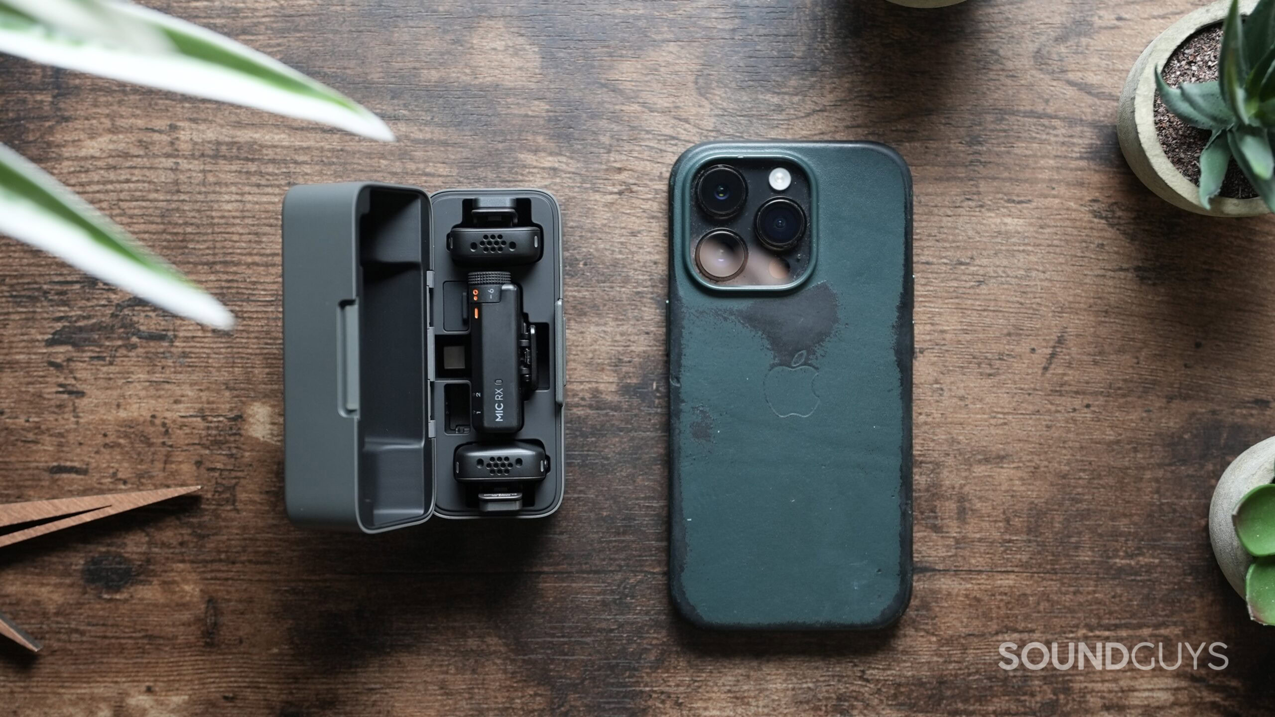 A full loaded DJI Mic Mini charging case next to an iPhone 14 Pro