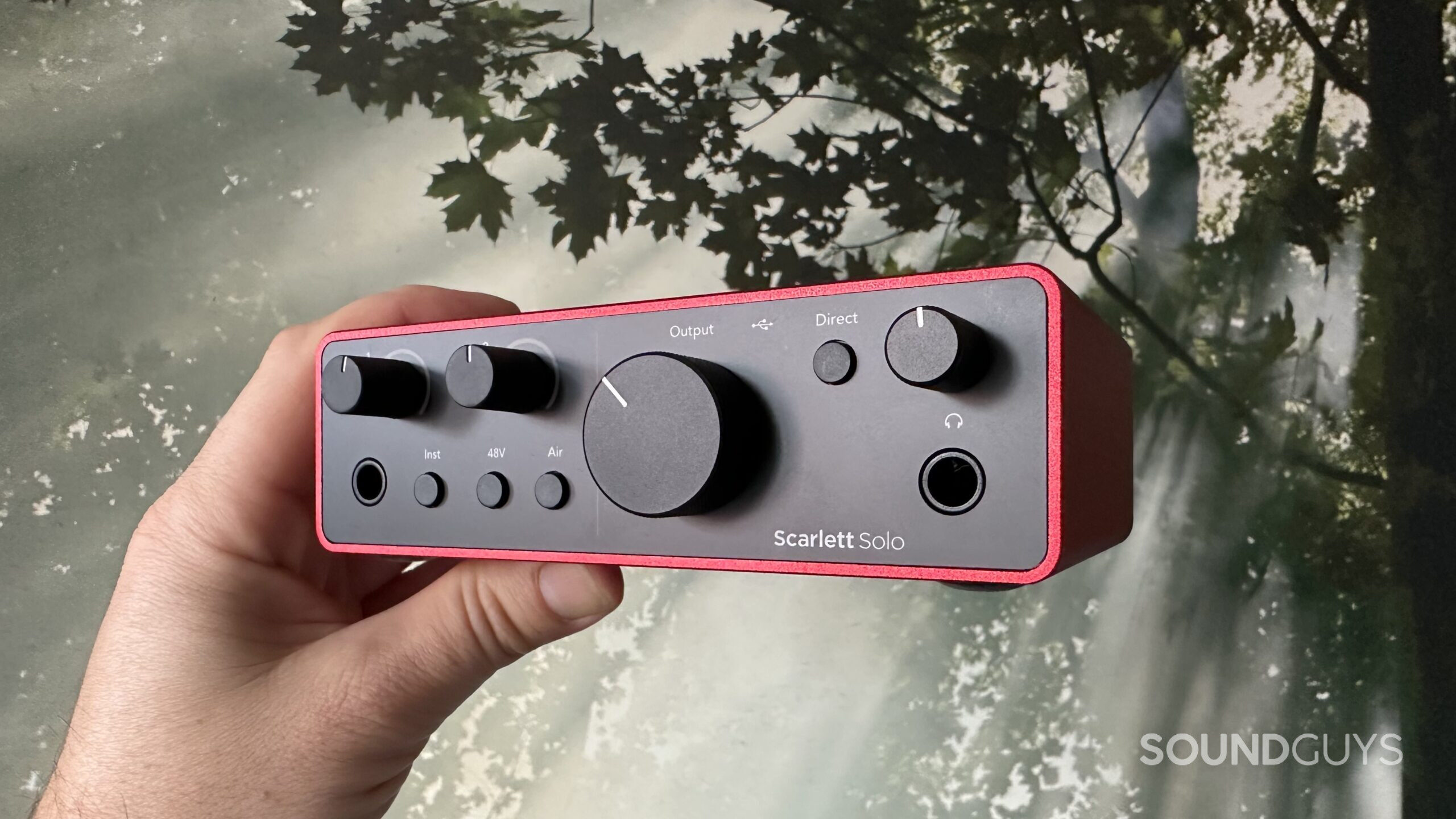 Photo of a hand holding a Photo of a Focusrite Scarlett Solo 4th Gen interface.