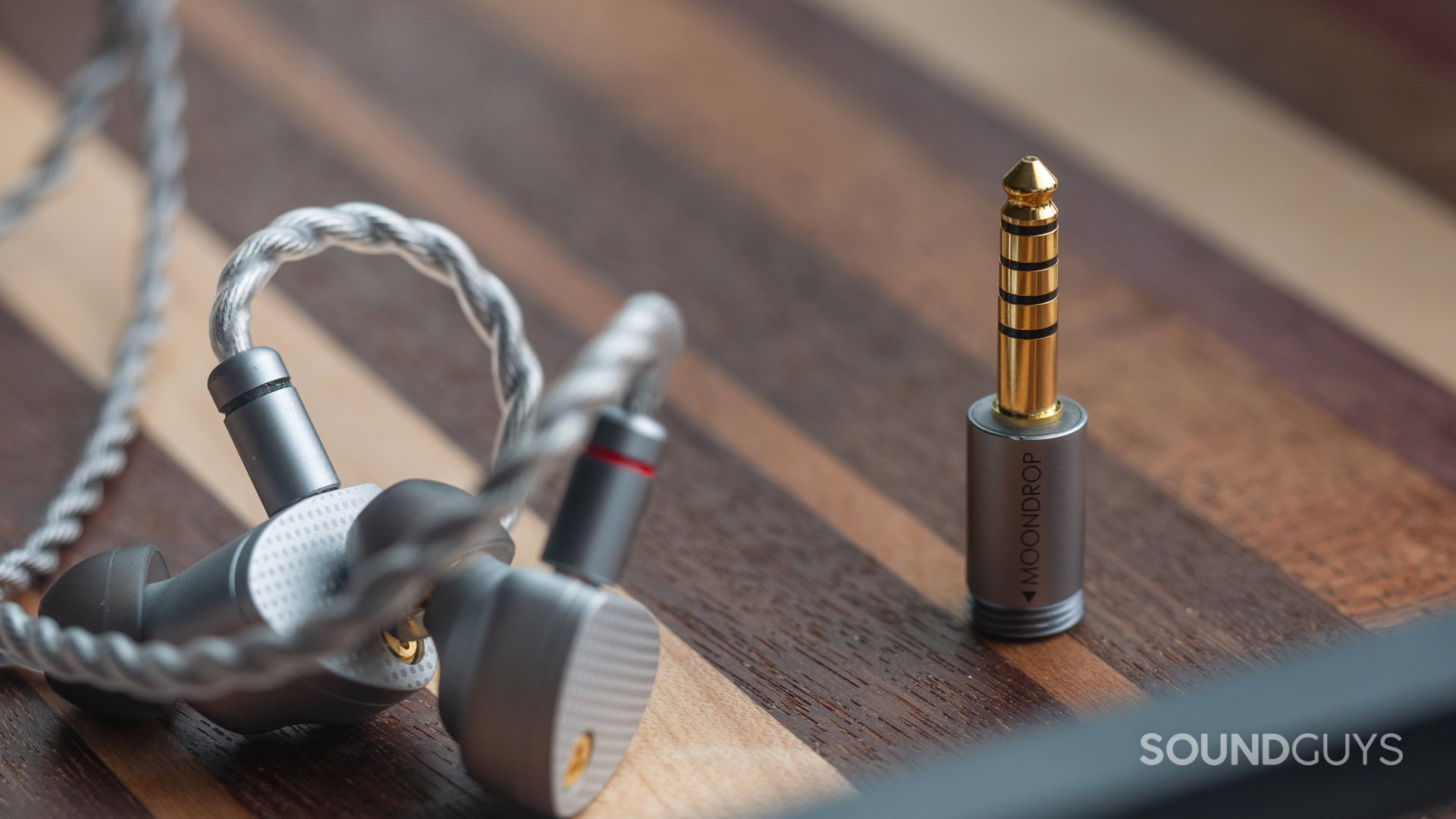 A photo of the Moondrop Aria 2 with the 4.4mm balanced connector sitting aside the earbuds.