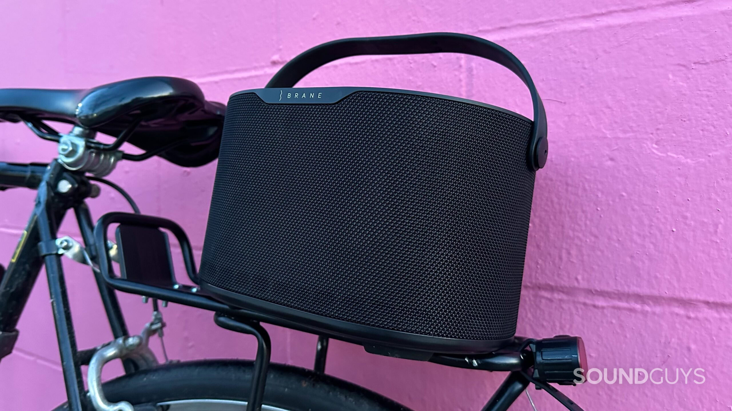 The Brane X speaker resting on a bike pannier rack above the rear tire.