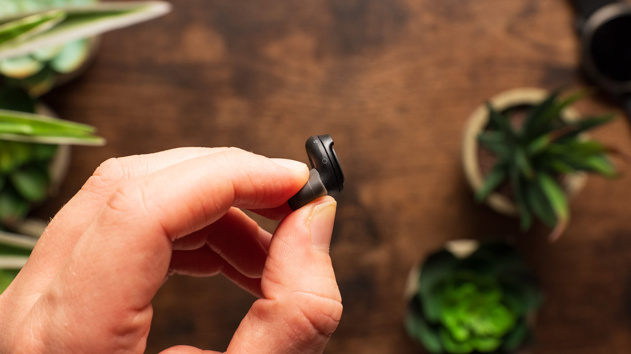 A hand holds the Loop Switch earplugs showcasing the mechanical switch.