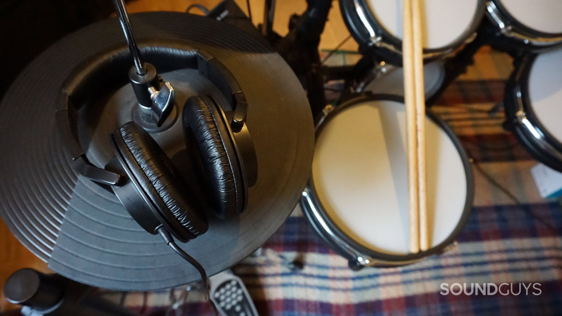 A photograph of the Roland RH-5 over-ear headphones and an electronic drum kit.