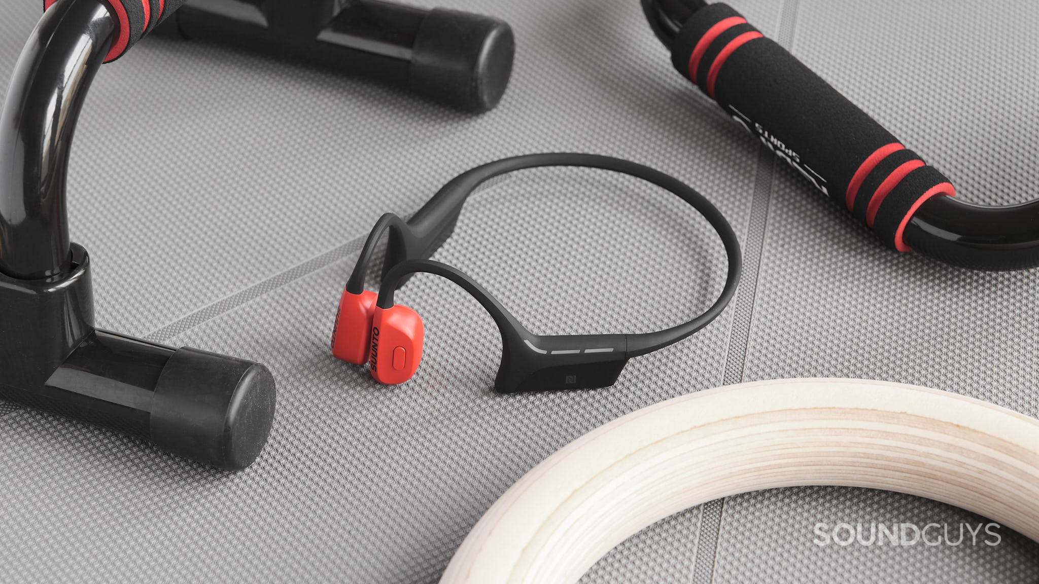 The Suunto Wing headphones next to workout equipment.