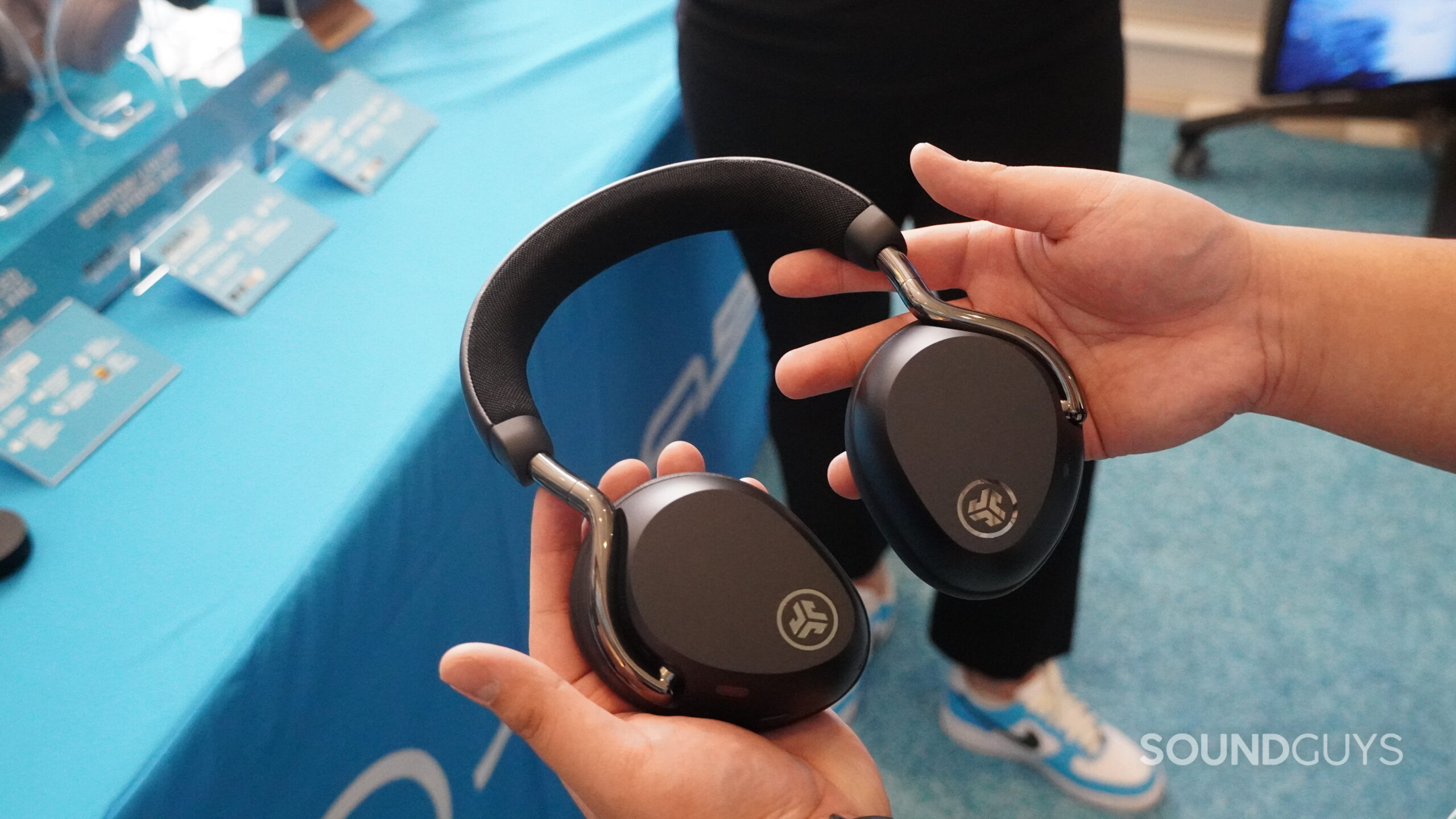 Hands hold the JLab Epic Lux Lab headphones