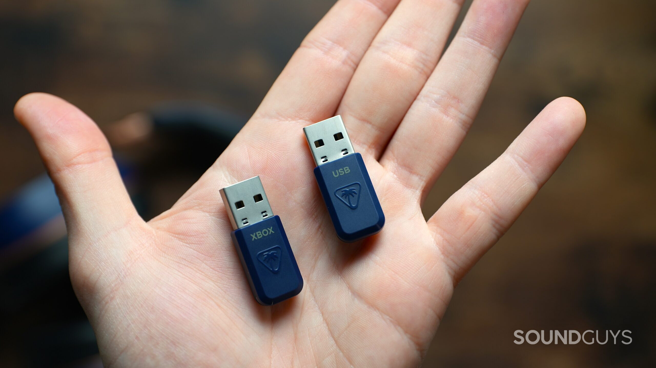 a hand holding two TB Stealth 700 Gen 3 USB dongles