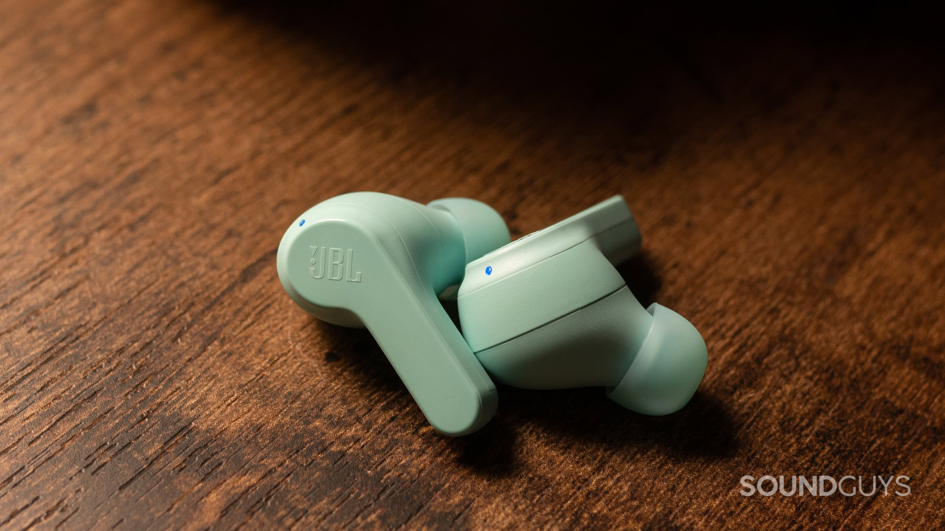 A close up photo of the JBL Vibe Beam sitting atop a desk.