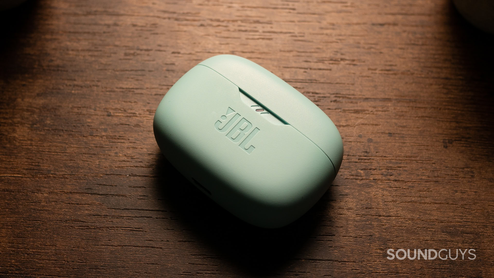 The charging case of the JBL Vibe Beam on a desk.