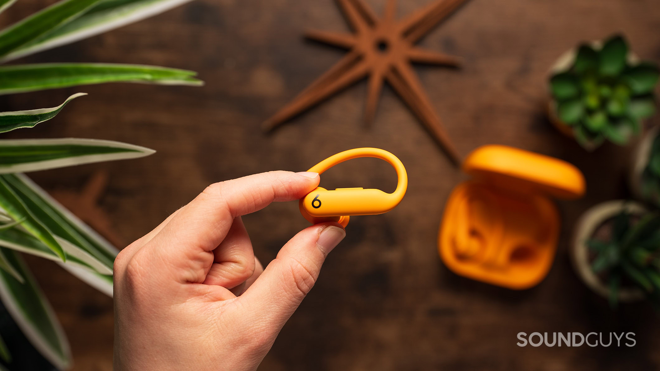 A hand holds a Powerbeats Pro 2 earbud.