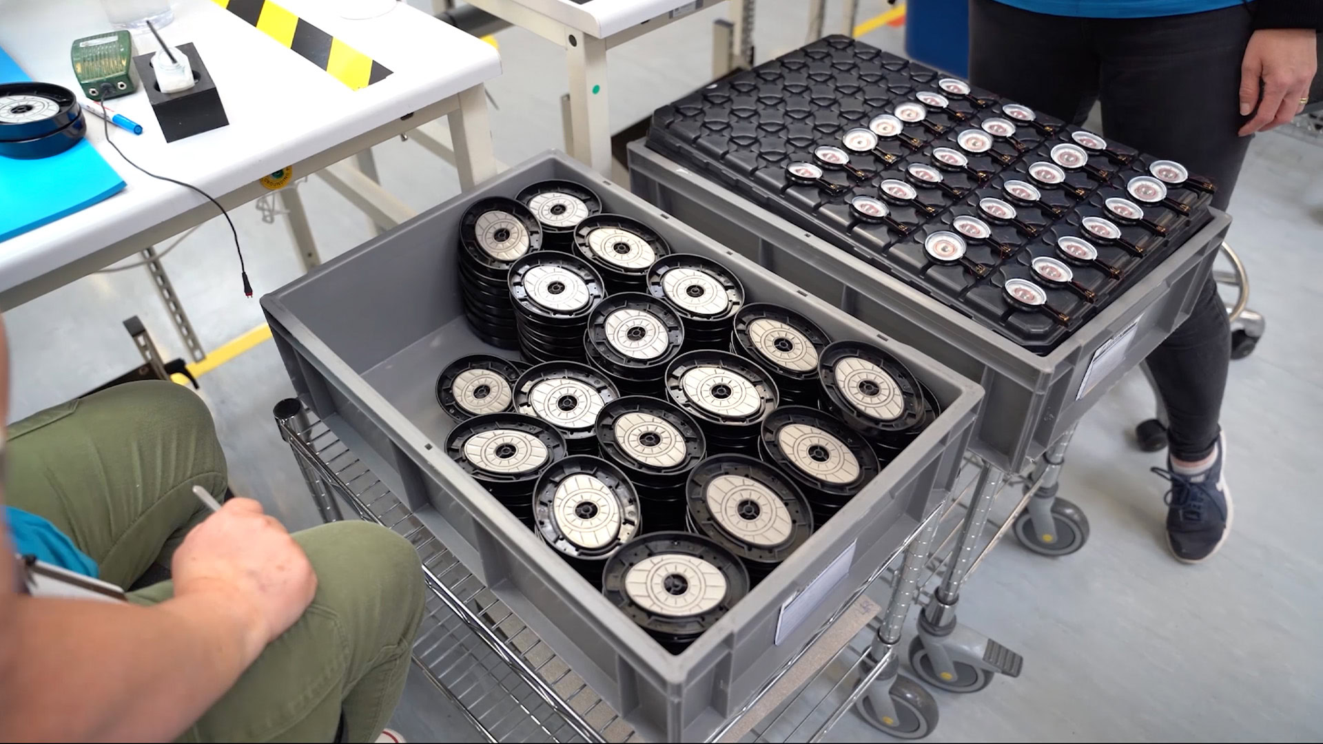 A photo of a factory floor with headphone components in a bin.